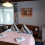 Comfortable hotel room with double bed, bedside lamps, small fridge and window with curtains.