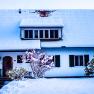 A snow-covered country house with a snow-covered roof and garden in winter.