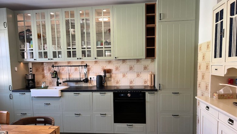 Kitchen with white cupboards, wooden worktop and tiled splashback.