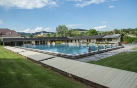 Krumbach outdoor pool with swimming pool and diving blocks, surrounded by green landscape and buildings.