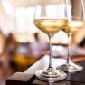 Two wine glasses with white wine on a table, blurred background.