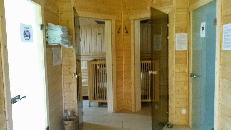 Interior view of a sauna with wooden walls, glass doors and towels.