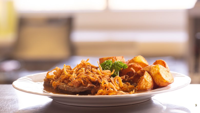 A plate of roast onions, fried onions and roast potatoes.
