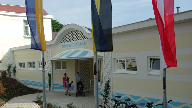 Entrance to a swimming pool with flags and bicycles in front of it.