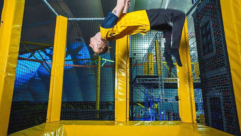 A person does a backflip on a trampoline in a hall.