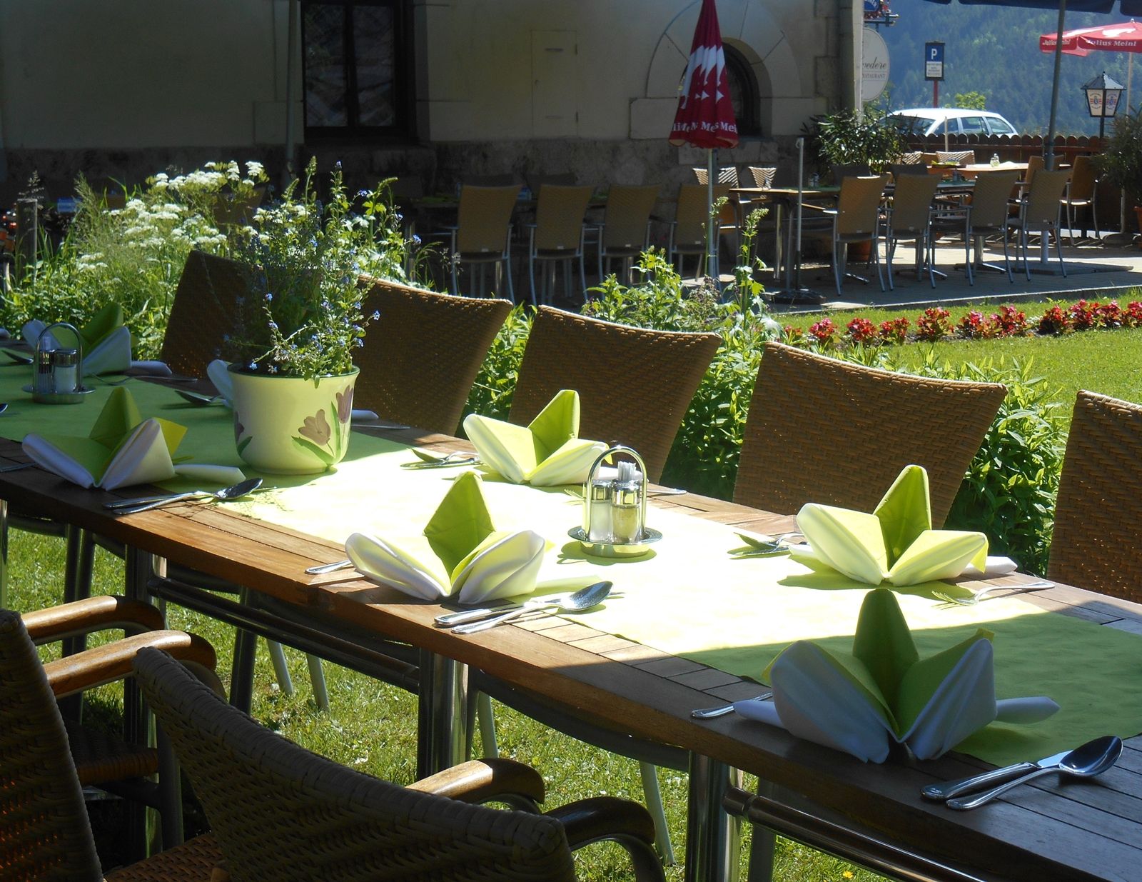 Table set in the garden with green napkins and flowers.