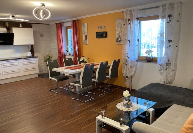 Modern eat-in kitchen with dining table, chairs, sofa and kitchenette.