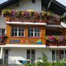 A vacation home with colorful flowers on the balconies and the lettering 'LUNZ Ferien'.