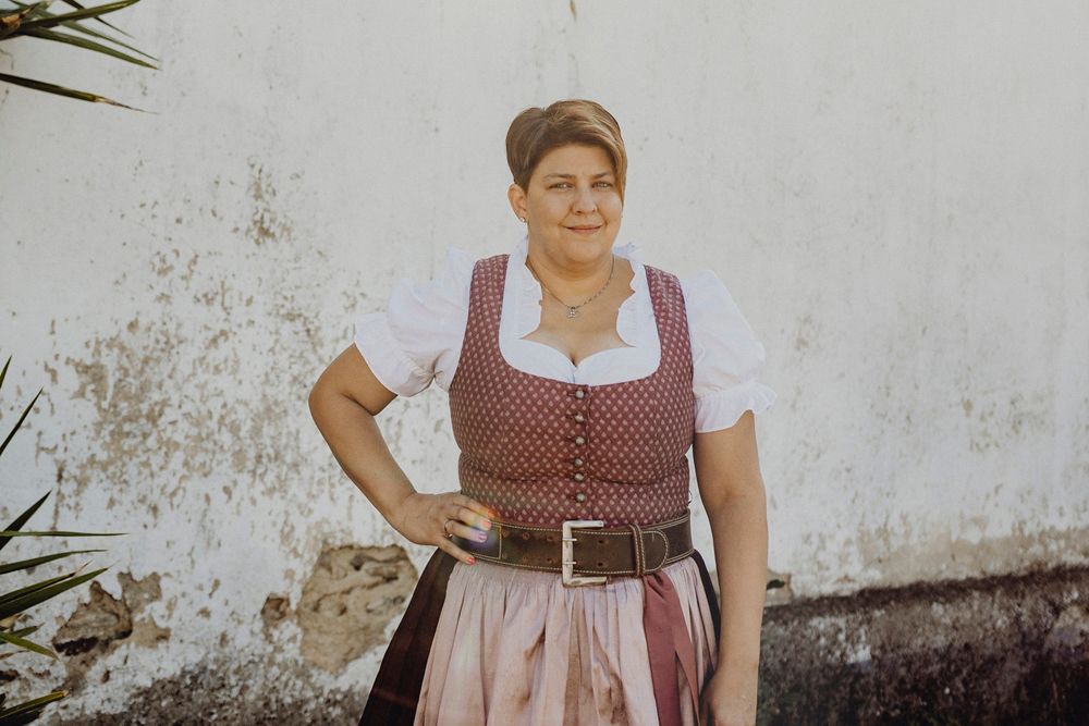 Woman in traditional costume in front of a white wall.