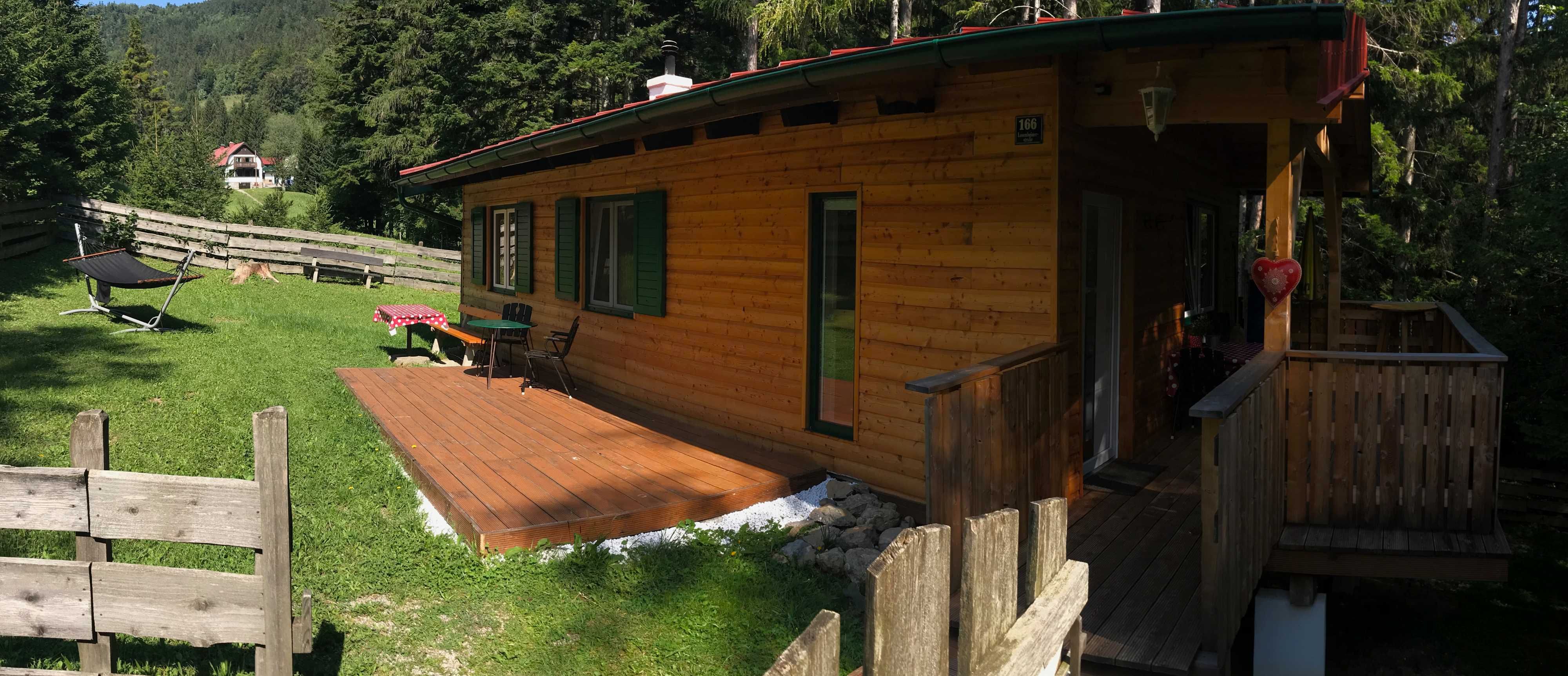 A wooden holiday home with terrace in a green, wooded setting.