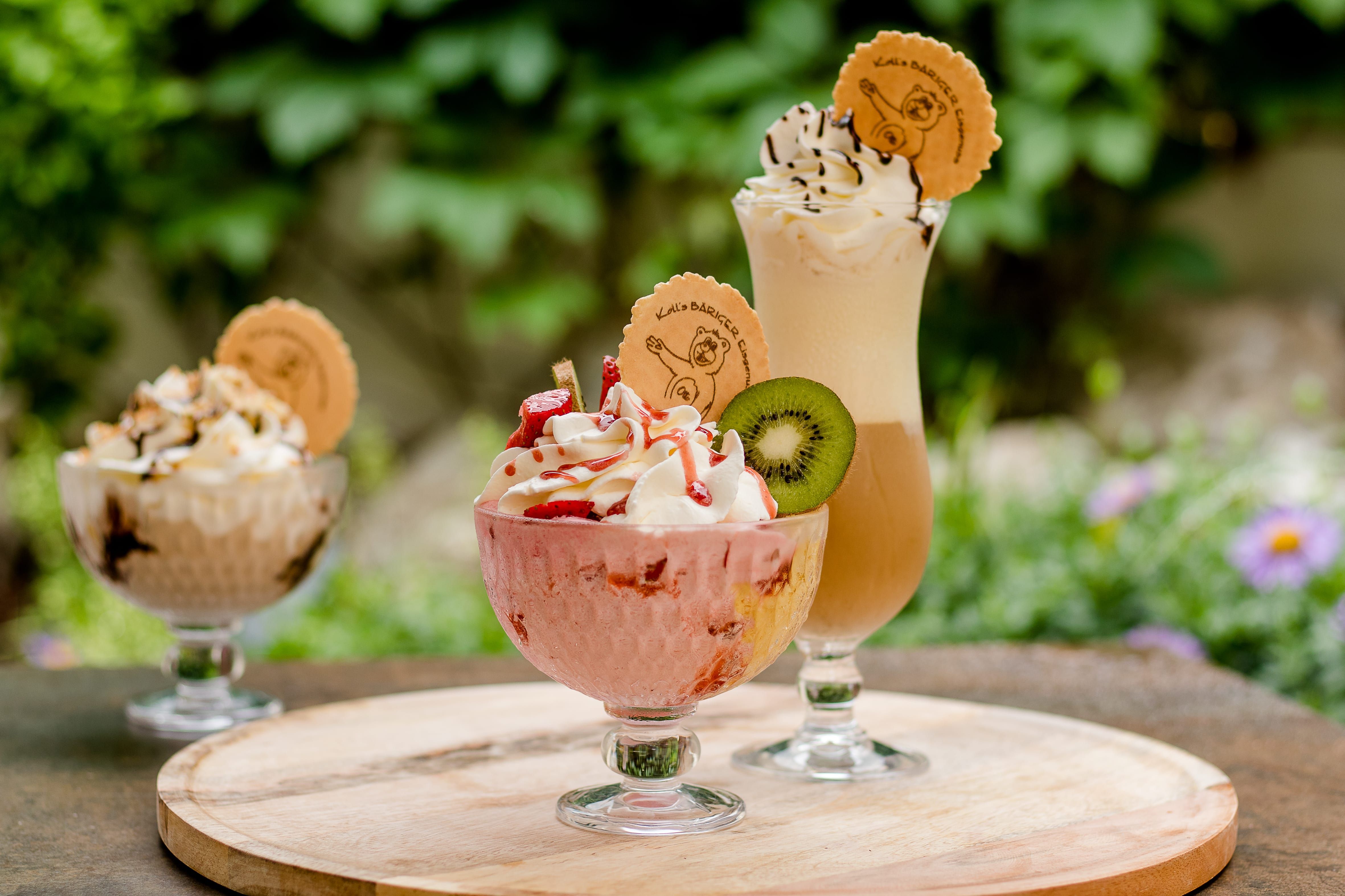 Three sundaes with cream and decoration on an outdoor table.