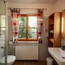 Modern bathroom with window, shower cubicle, washbasin and shelves.