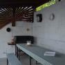 Covered barbecue area with table and benches, decorated with crockery on the wall.
