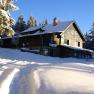 Snow-covered hut in the forest in the sunshine.