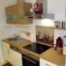 Modern kitchen with wooden worktop, stove, sink and coffee machine.