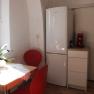 Small kitchen with table, red chairs, fridge and coffee machine.