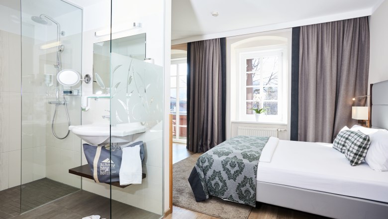 Modern hotel room with double bed and glass shower.