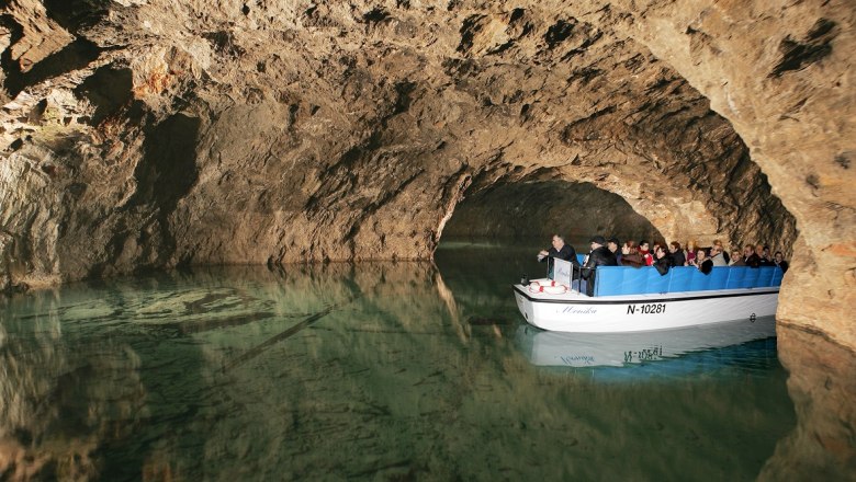 Boat tour in an underground cave with tourists on a small boat.