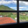 View from a window of a rural landscape with vineyards, houses and a hill in the background.