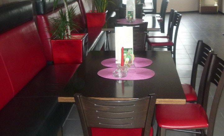 Interior view of a café with red and black furniture, plants and a dart machine.