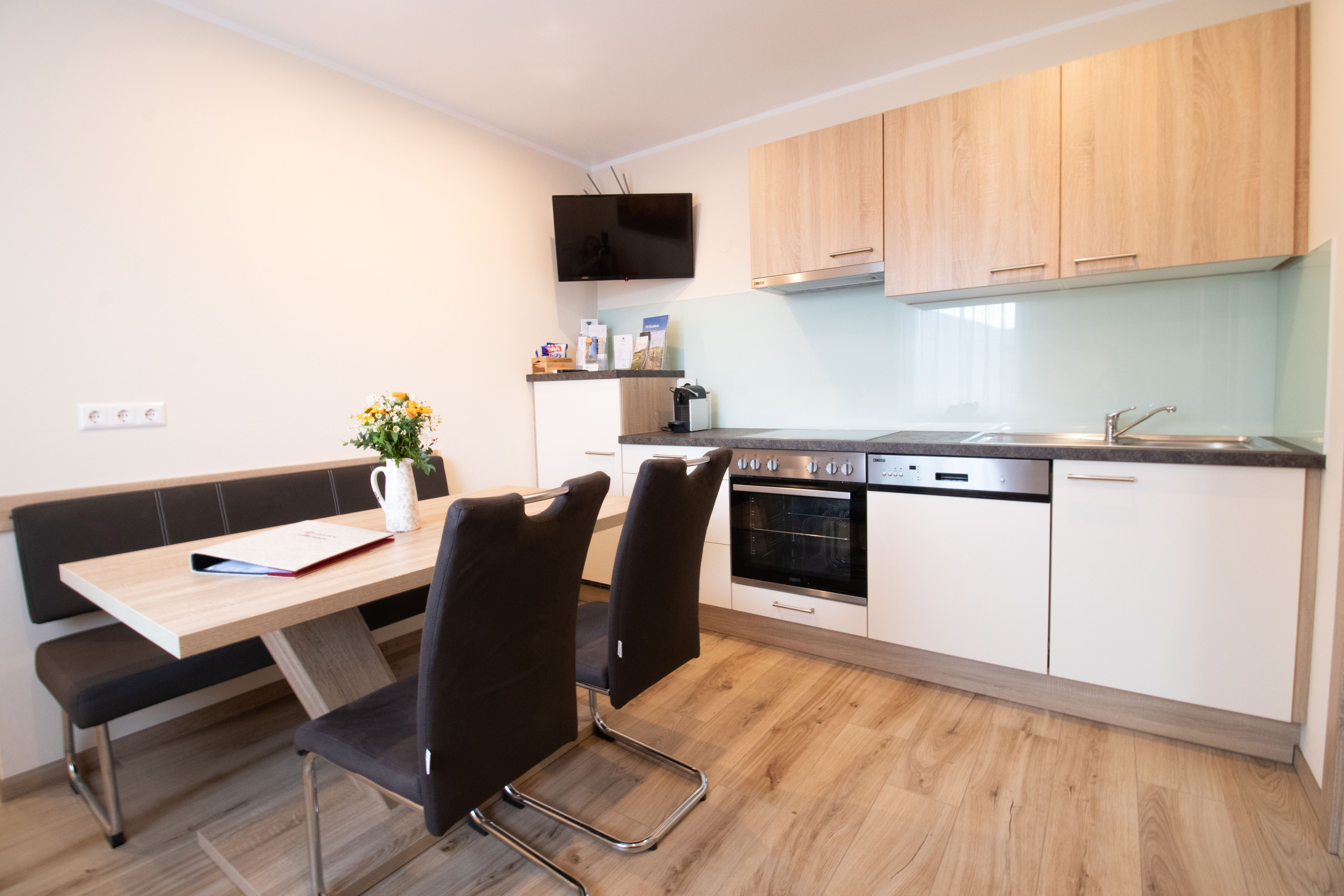 Modern kitchen with a dining table, chairs, and kitchen appliances.