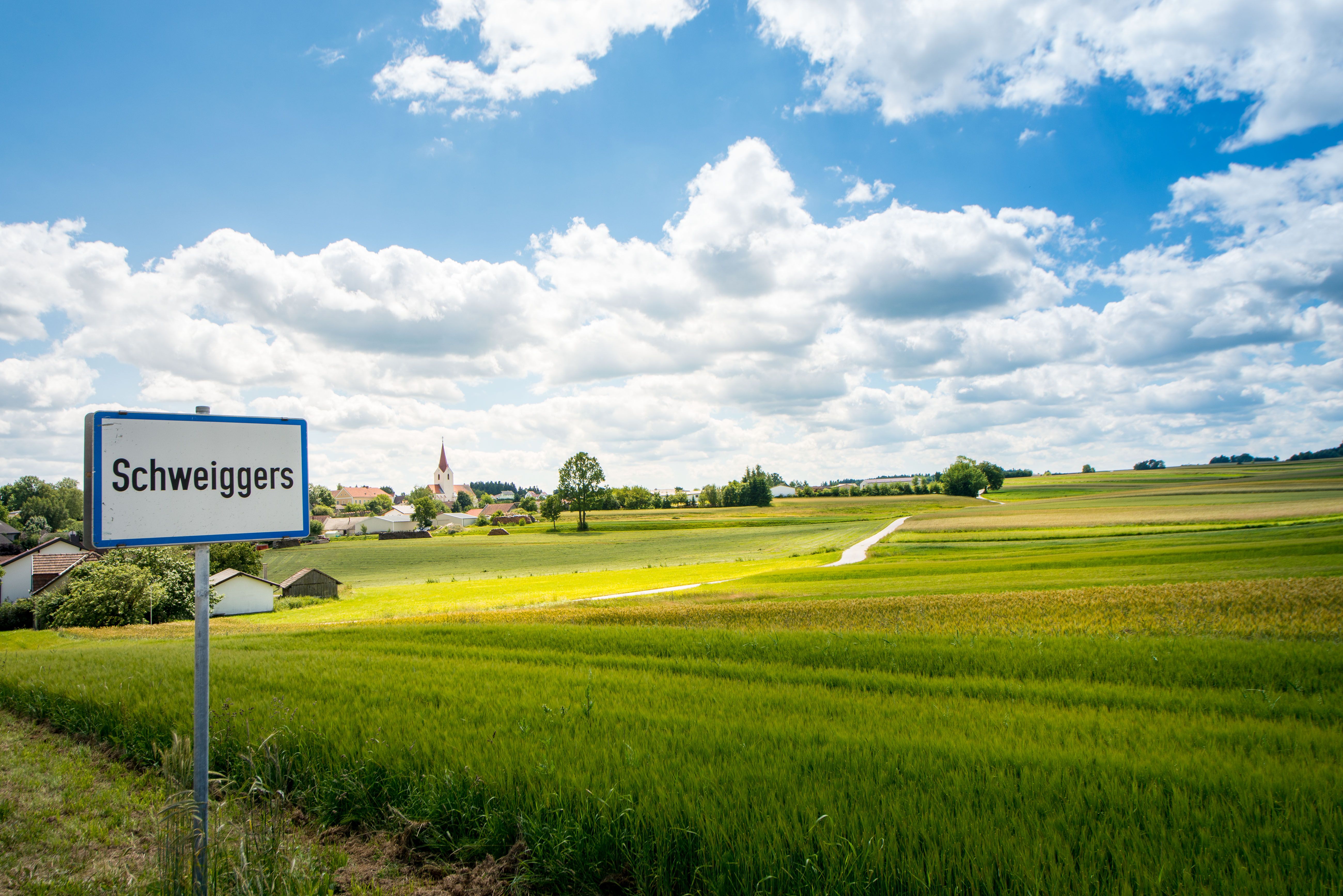 Schweiggers village sign with a view of green fields and houses