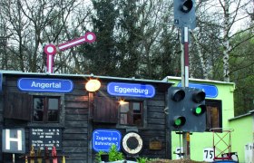 Model railroad with trains in front of a small building with signs 'Angertal' and 'Eggenburg'.