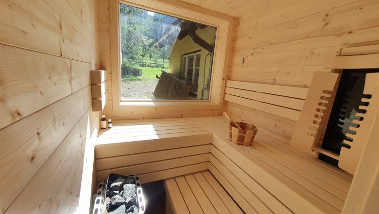 Interior view of a modern sauna with wood paneling and large window.
