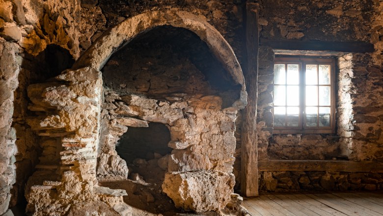 Old oven in a stone room with wooden floor and window. Located in the attic of the Lichtenegg fortified church.