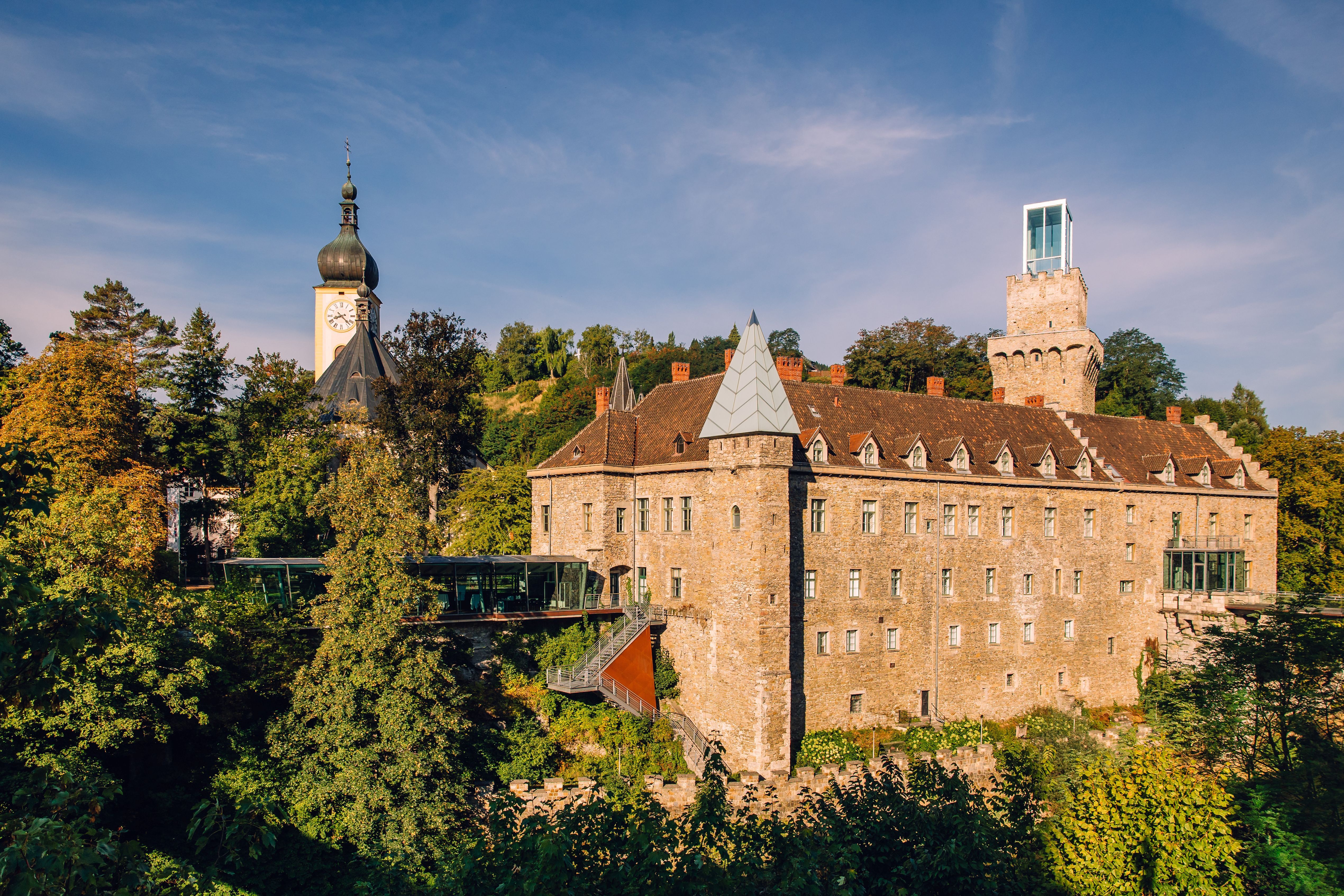 Schloss Rothschild in Waidhofen an der Ybbs, with its striking castle tower and modern glass architecture, surrounded by green trees.