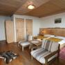 Cozy double room with wooden furniture, double bed, armchairs and carpet.