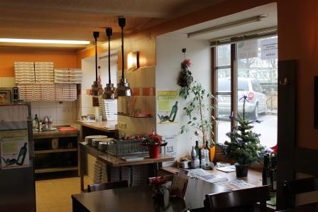 Interior view of a pizzeria with tables, chairs and decorations.