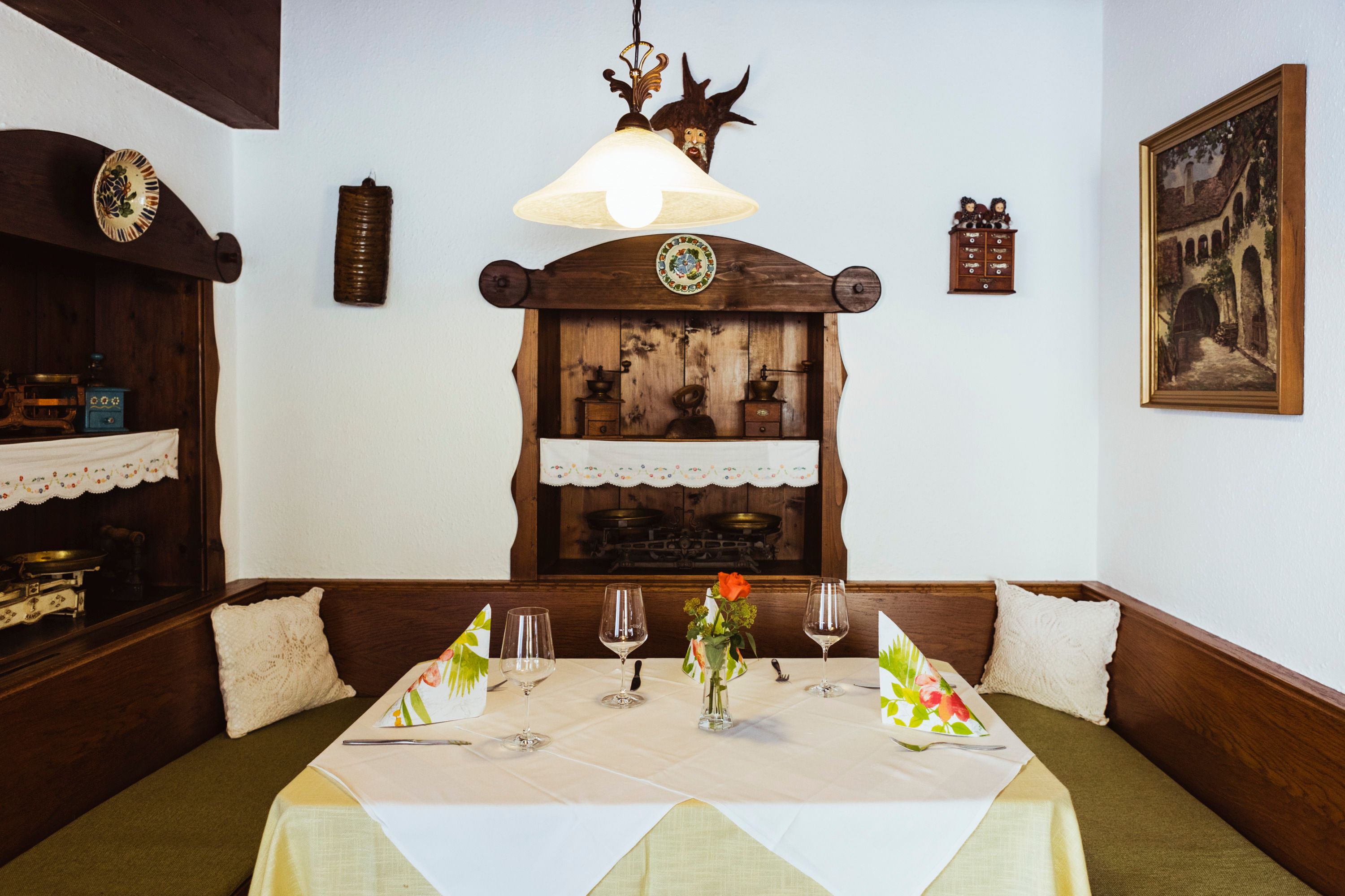 Cozy seating area in a restaurant with wooden furniture, decorative details and table setting.
