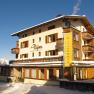 A hotel in the snow with balconies and blue sky in the background.