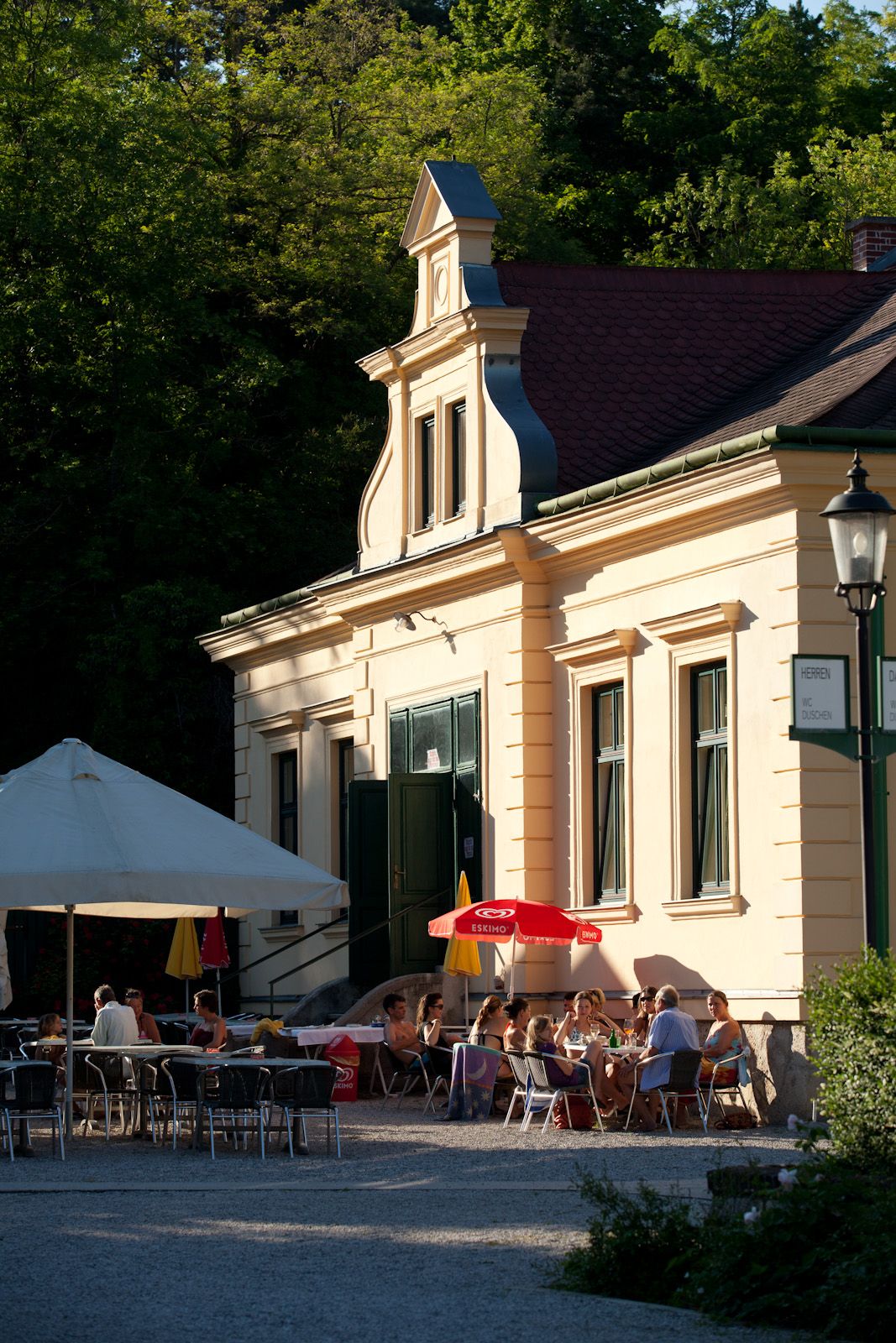 Exterior view of a restaurant with parasols and guests outside.