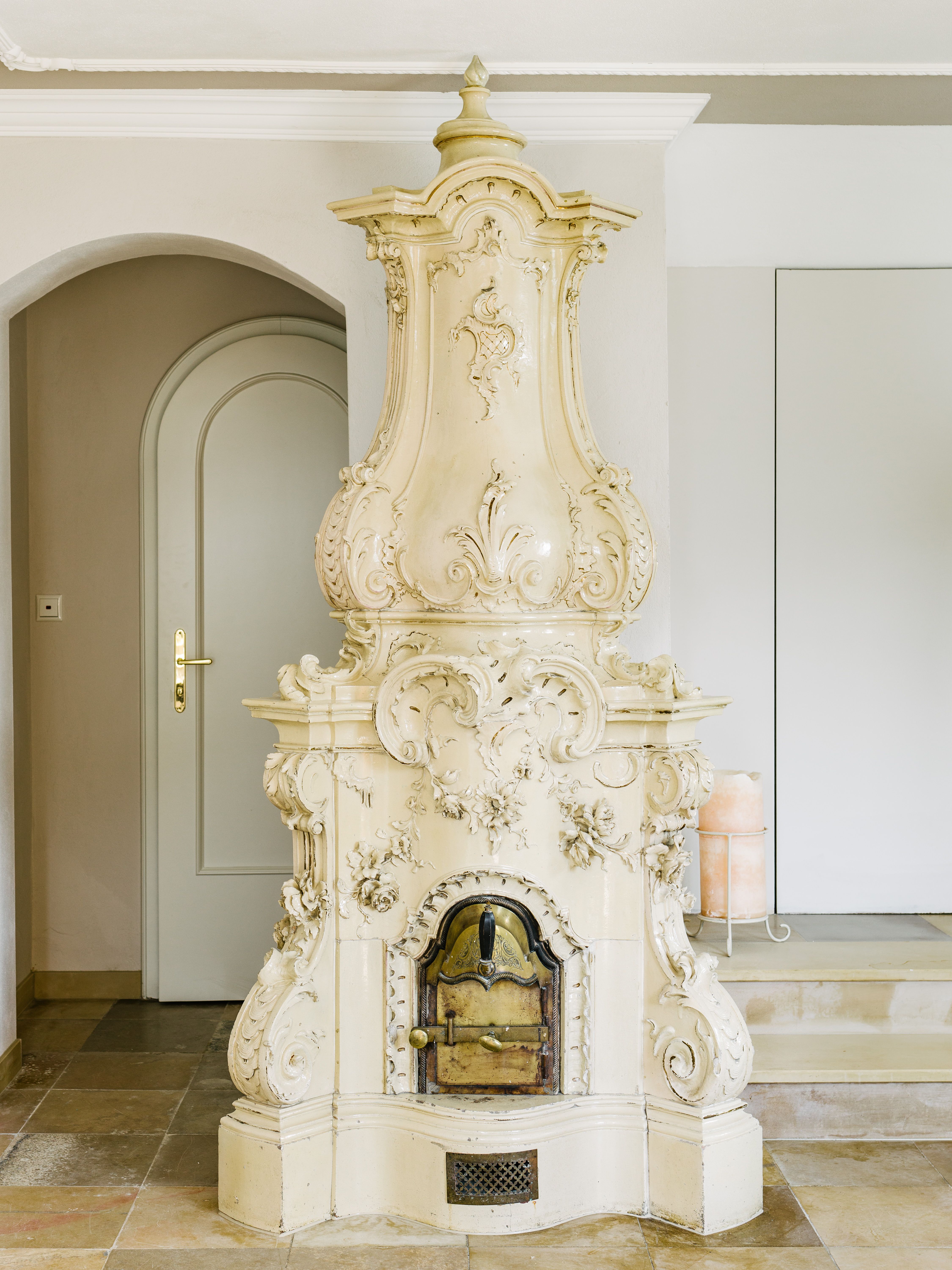 An ornate, antique fireplace in a room with a tiled floor.