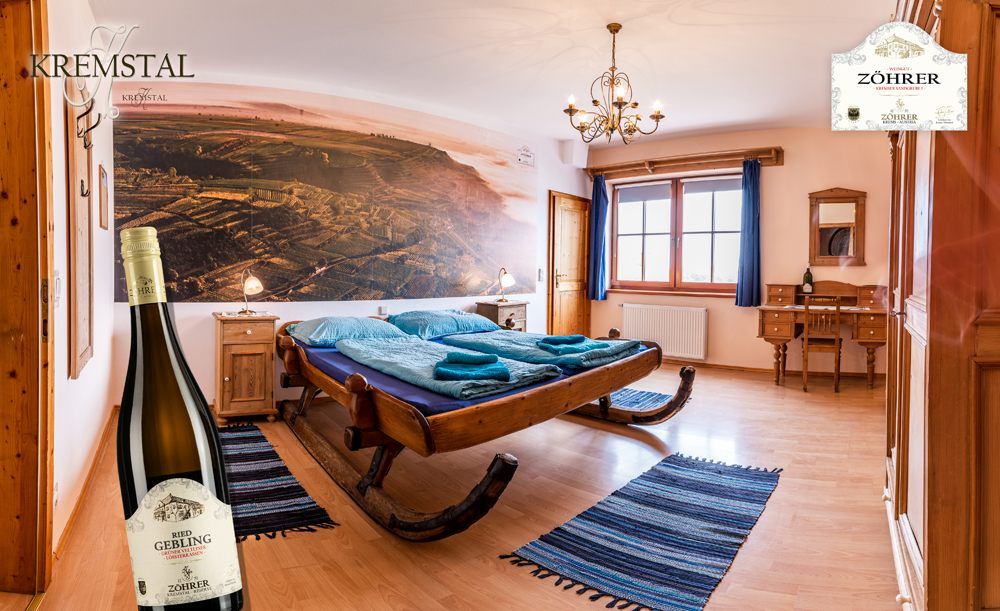 Cozy room with sleigh bed, wooden furniture and large mural. A bottle of wine stands in the foreground.
