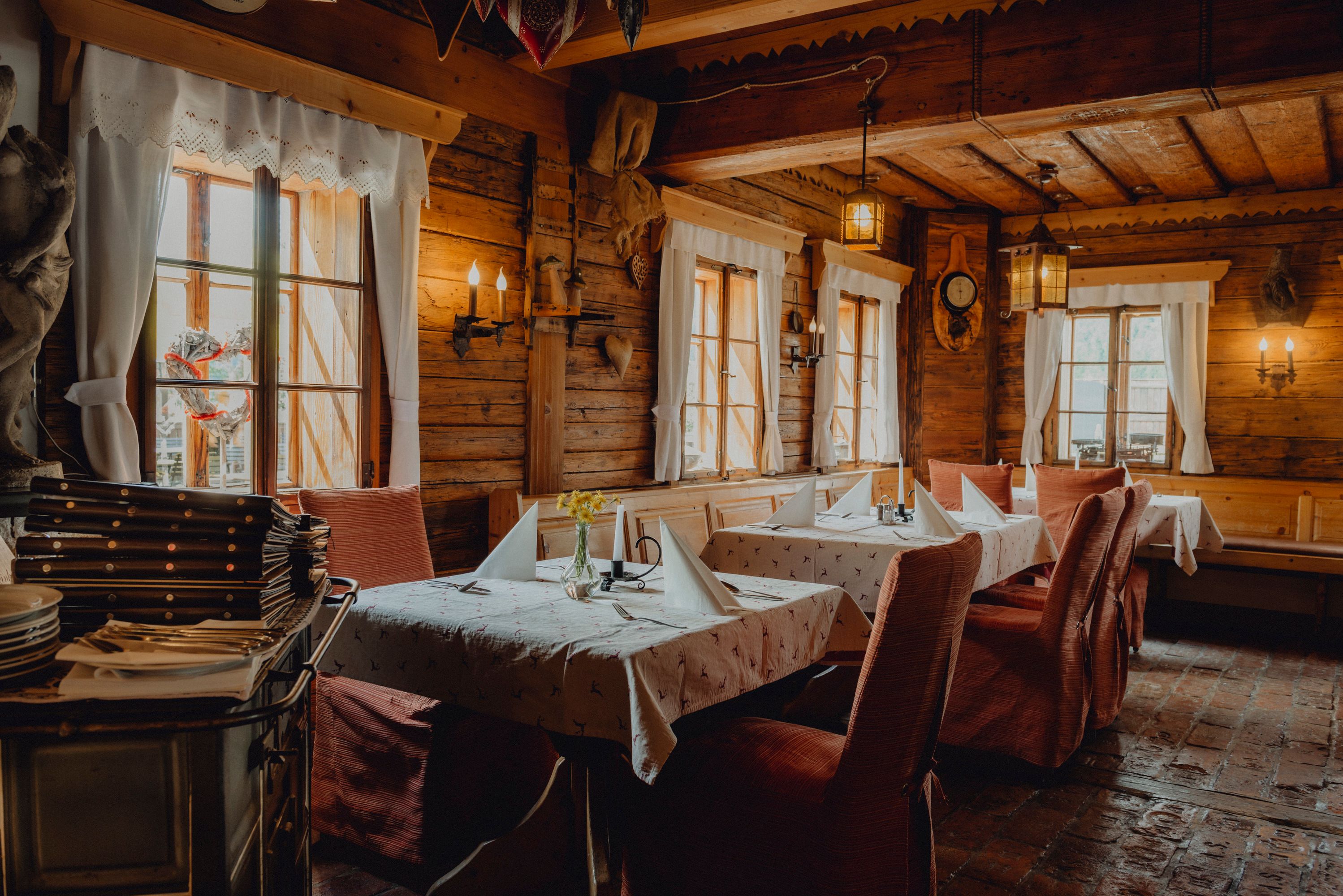 Interior view of a rustic restaurant with wooden walls and laid tables.