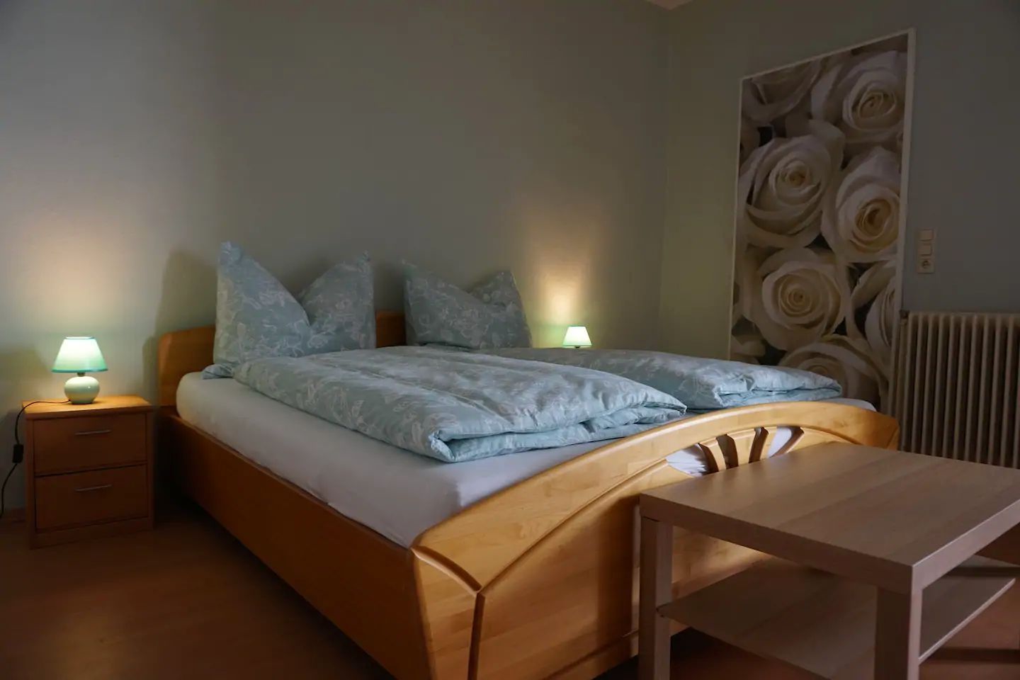 Bedroom with double bed, bedside tables and table.