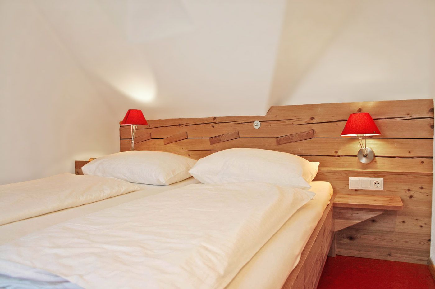 Guest room with wooden bed and red lamps.