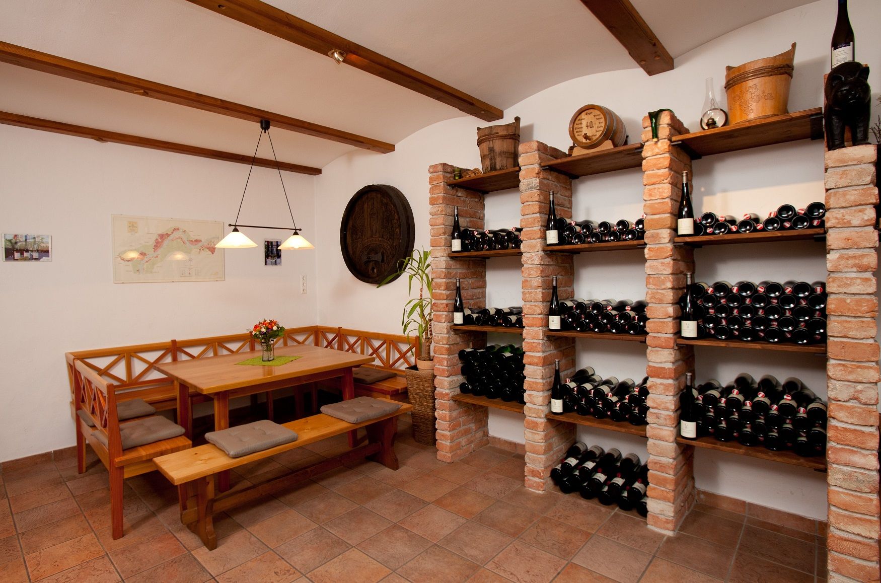 A wine cellar with a table and benches for tasting, surrounded by wine racks full of bottles.