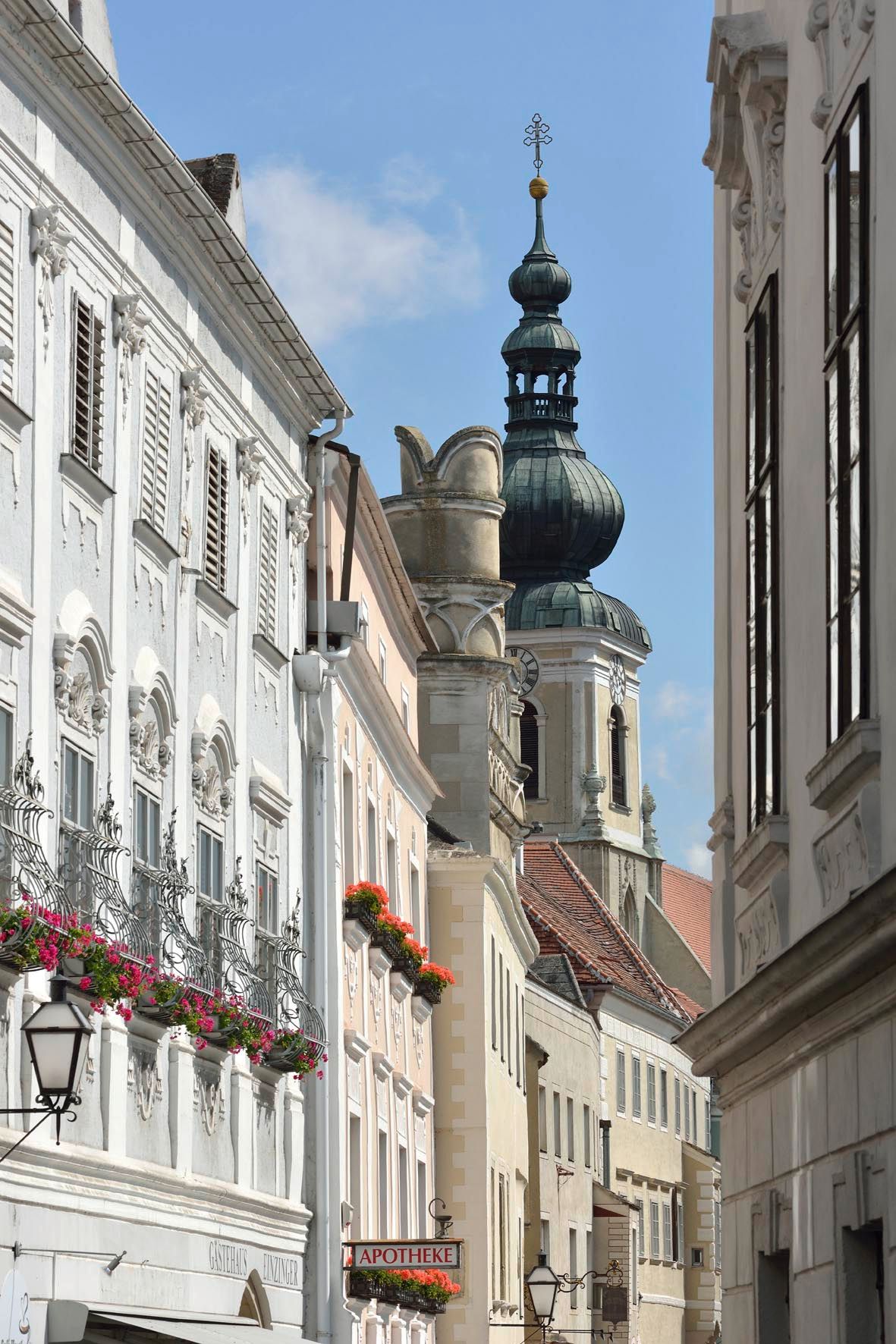 Street scene with historic buildings and church tower in the background.