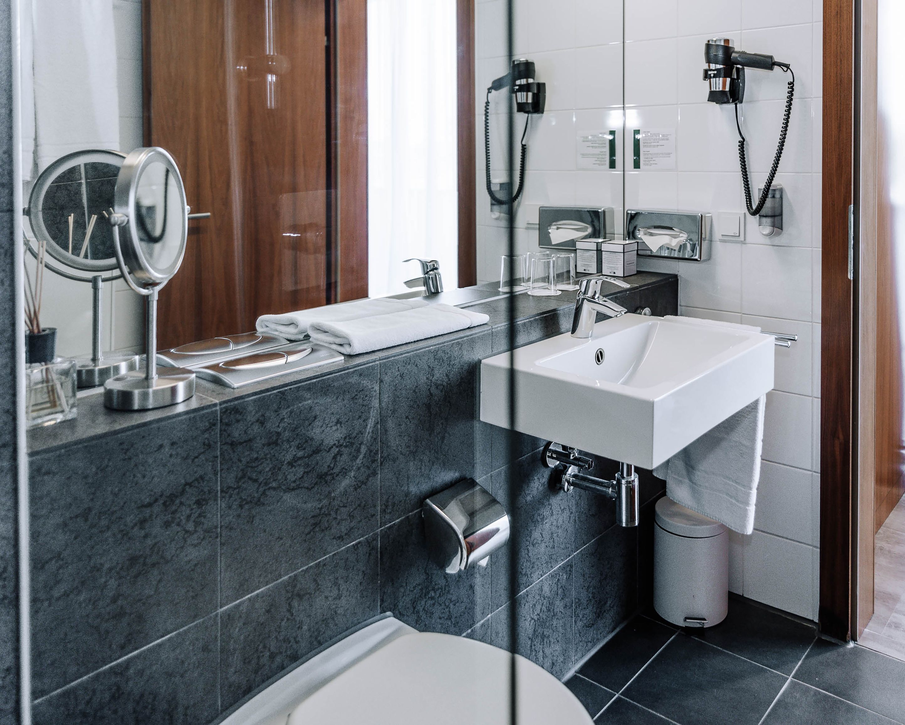Modern hotel bathroom with washbasin, mirror and towels.
