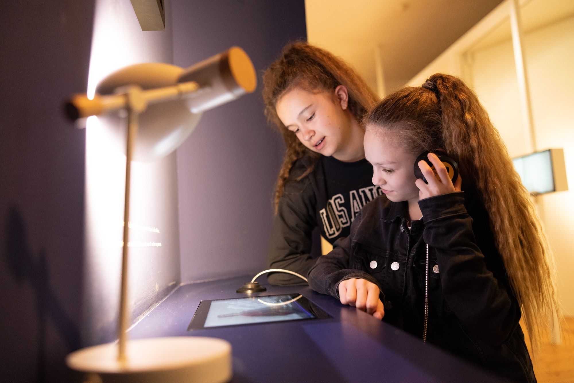 Two girls interact with a digital exhibition in a museum.