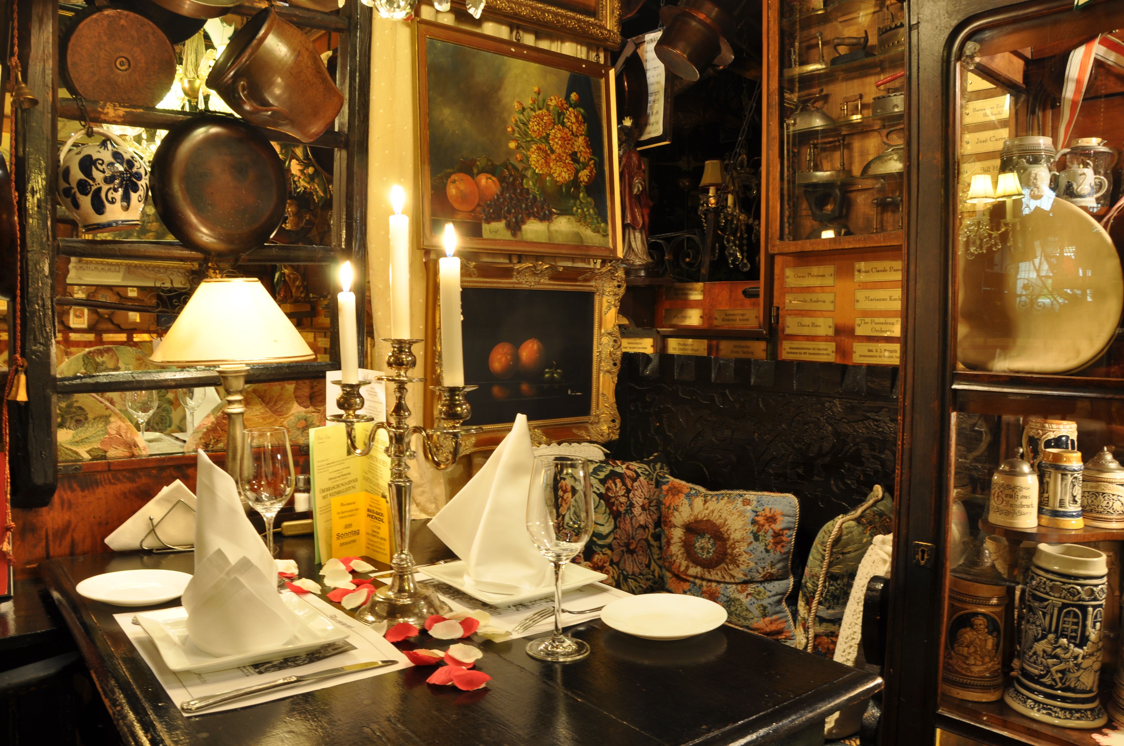 Comfortably decorated table in a rustic restaurant with candlesticks, pictures and antique objects.