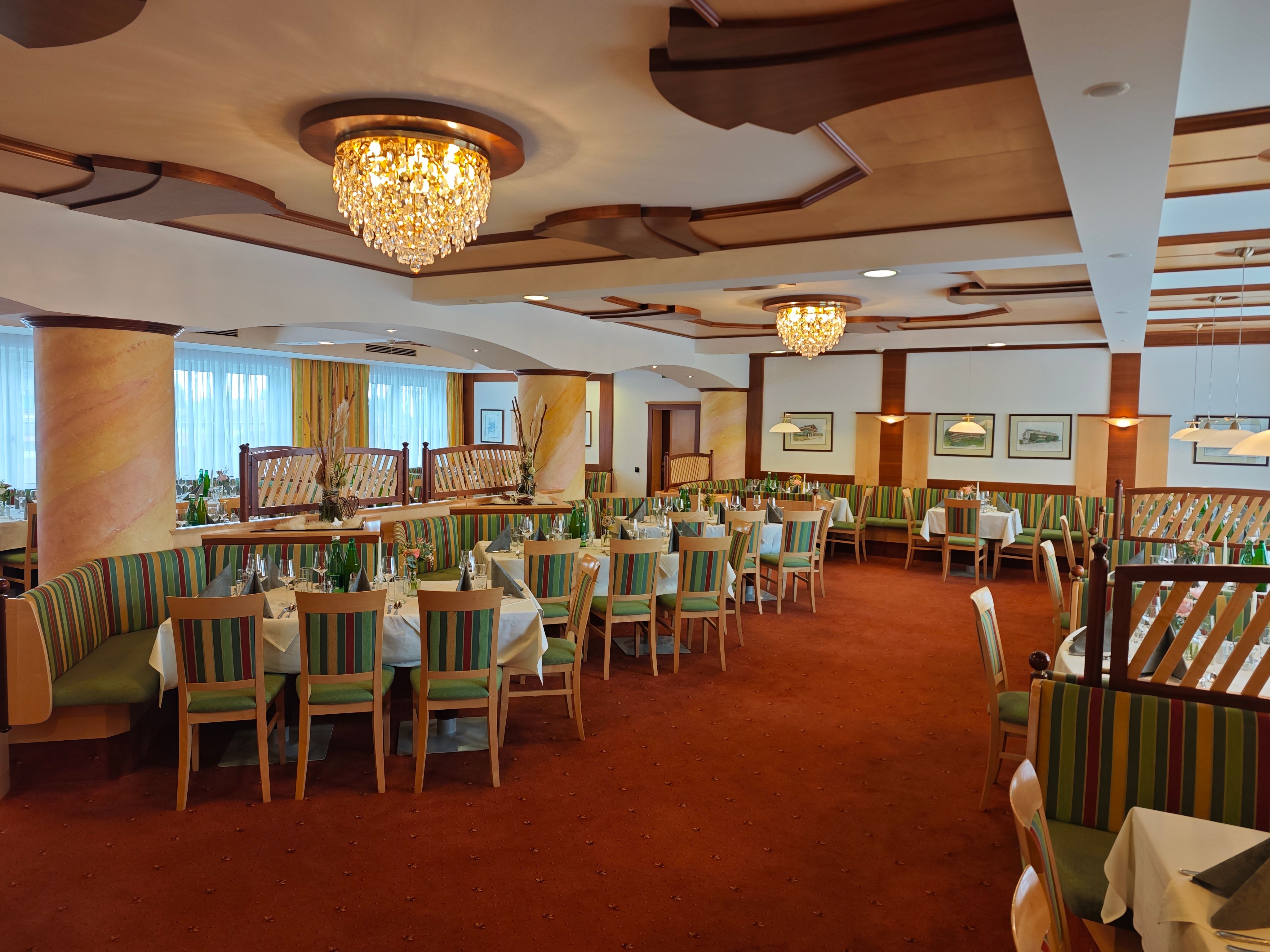 An elegant dining room with chandeliers and set tables at the Hotel Thier.