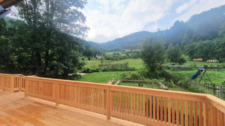 View from a terrace of a green landscape with trees and hills in the background.