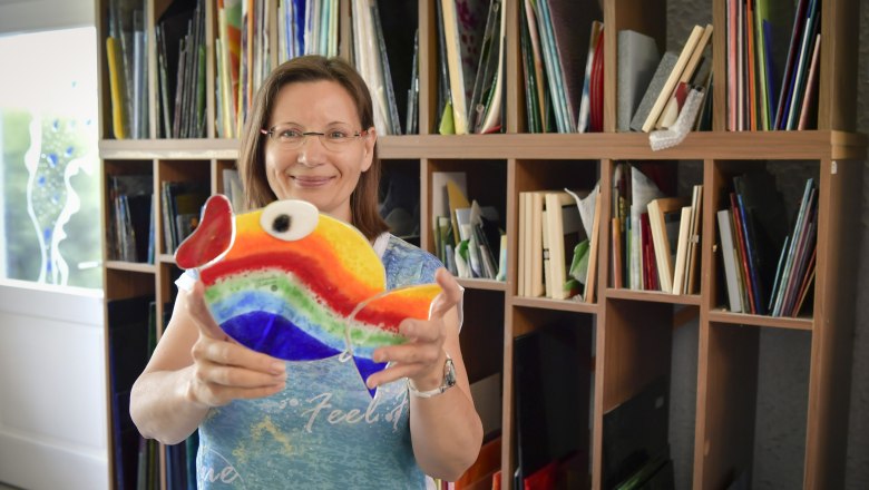 Woman holding colorful glass fish in a studio.