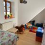 Children's room with bed, toys and colorful carpet.