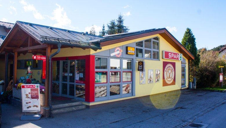 Exterior view of a bakery and a Spar supermarket in the sunshine.
